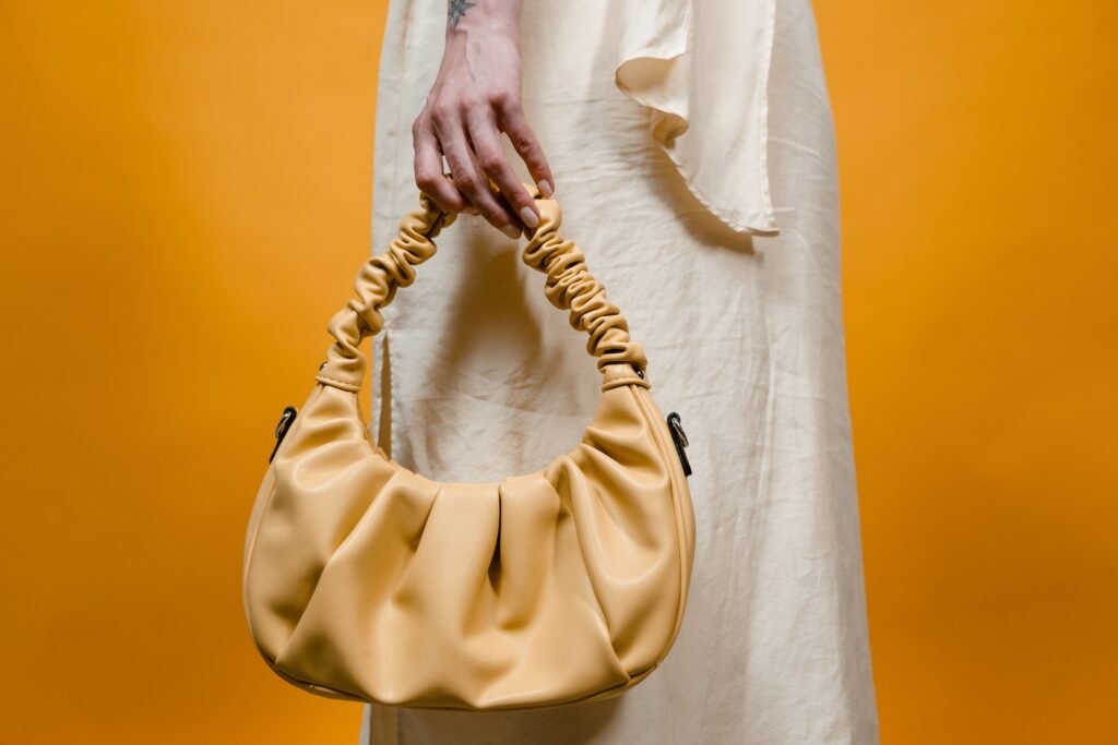 Stylish yellow handbag held against a vibrant background, perfect for fashion themes.